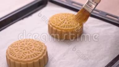 中秋节制作月饼的过程-妇女在烘焙前在糕点表面刷蛋液。 节日自制